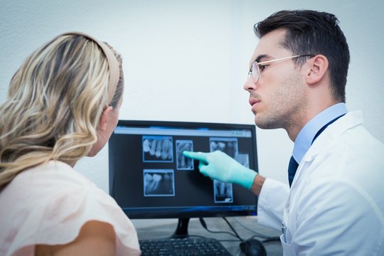 Dentist showing woman her mouth x-ray on computer