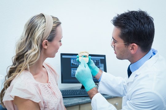 Dentist showing woman prosthesis teeth