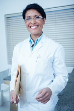 Smiling female dentist holding folder