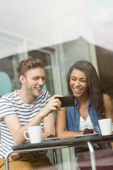 Smiling friends with chocolate cake using smartphone