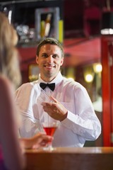 Handsome barman smiling at camera making a cocktail