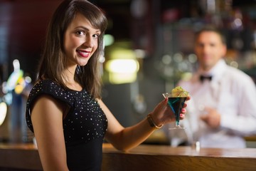Pretty brunette smiling at camera with cocktail