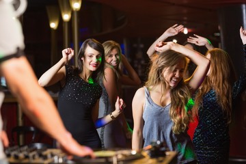 Happy friends dancing by the dj booth - obrazy, fototapety, plakaty
