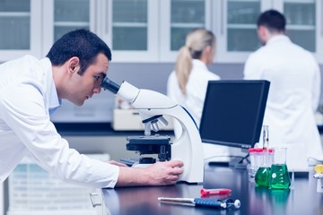 Naklejka na ściany i meble Science student working with microscope in the lab
