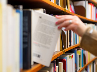 woman selecting a book from book shelf