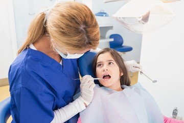 Pediatric dentist examining her young patient