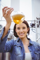 Woman looking at camera while holding beaker of beer