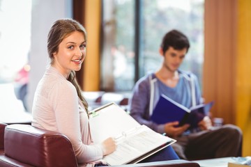 Students sitting on couch revising and smiling at camera