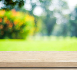 Naklejka na ściany i meble Empty wood table with blur green leaves bokeh background