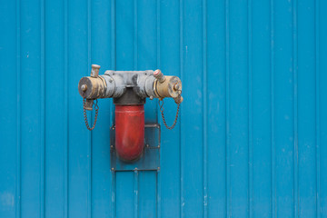 Fire Hydrant mounted on blue wall.