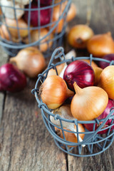 red and yellow onion in an iron basket on wooden surface