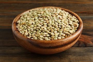 Green lentil in a wooden bowl on wood closeup
