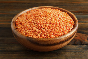 Red lentil in a wooden bowl on wood closeup