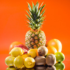 Still life pineapple and various fruits on orange background