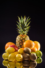 Still life pineapple and various fruits on black background