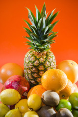Still life pineapple and various fruits on orange background
