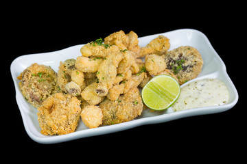 A basket of crispy chicken fingers with platter of vegetables an