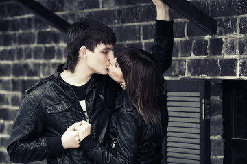 Happy young fashion couple kissing at the wall