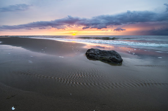 Fototapeta kamień na morskiej plaży podczas zachodu słońca