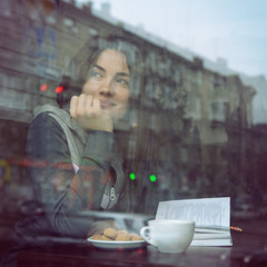 Young woman drinking coffee and reading book sitting indoor in u