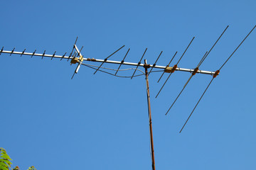 Old TV antenna on house roof with bule sky