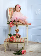 Little girl dressed as a ballerina in a tutu sits on a beautiful