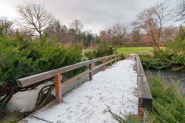 Landscape with first snow on a wooden bridge in Japanese garden