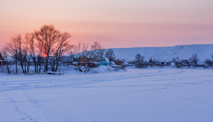 Winter landscape with the frozen pond and village