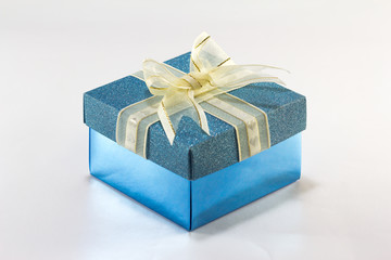 Blue gift box with gold ribbon and bow on white background