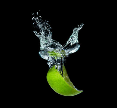 lime slices falling into water on black