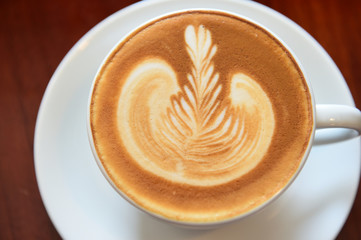 cup of latte art coffee on wooden background