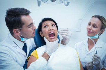 Dentist with assistant examining womans teeth