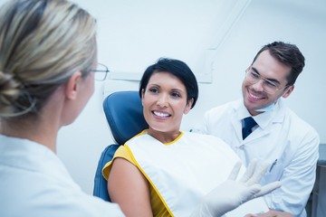 Smiling dentist and assistant with female patient