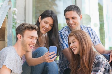 Obraz premium Happy students looking at smartphone outside on campus