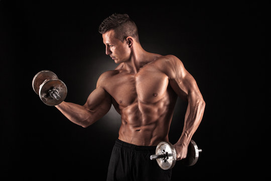 Muscular man with dumbbells on black background