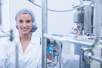 Portrait of a smiling scientist behind metal pipe