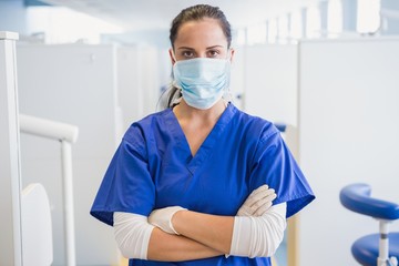 Fototapeta na wymiar Dentist wearing surgical mask with arms folded