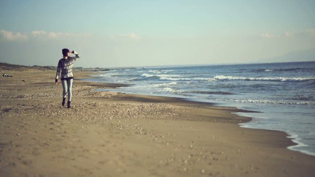 Teen girl walking on the beach. Handheld shot