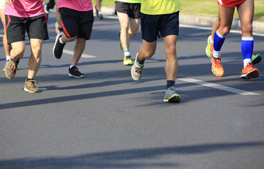 Naklejka premium marathon athletes legs running on city road