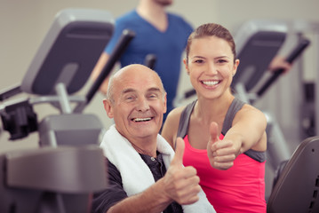 senior-kunde und trainerin zeigen daumen hoch