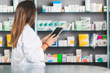 Beautiful Pharmacist with Digital Tablet in a Drugstore