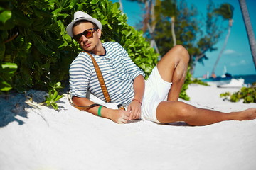 Stylish man model lying on beach sand