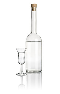 Spirituosenflasche und hohes Klechglas mit klarer Flüssigkeit