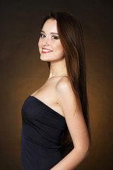 Fototapeta premium Beautiful young woman with long hair on dark brown background