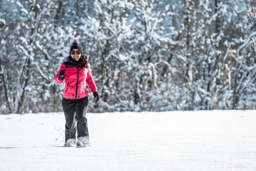 Fototapeta na wymiar Young woman running through the snow