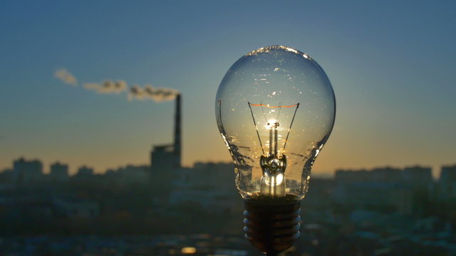 The incandescence bulb by the industrial city background