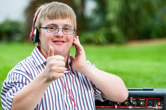 Down syndrome boy with headset doing thumbs up.