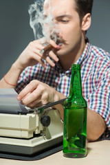 Author smoking cigar and drinking alcohol at typewriter