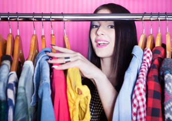 Young surprised woman searching for clothing in a closet