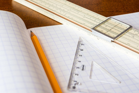 Schemes the pencil and triangle with slide rule on the table 